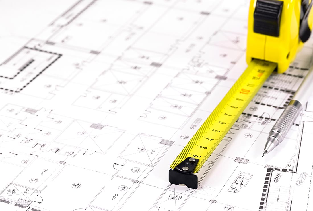 Measuring tape on architectural plans, illustrating construction project details for Bear Essentials handyman services.