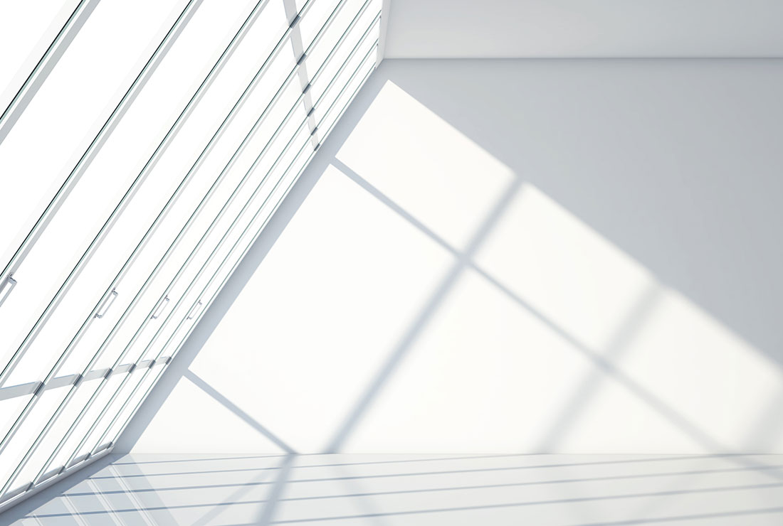 Modern interior space with large glass windows casting geometric shadows on a white wall and floor, emphasizing clean lines and minimalist design.