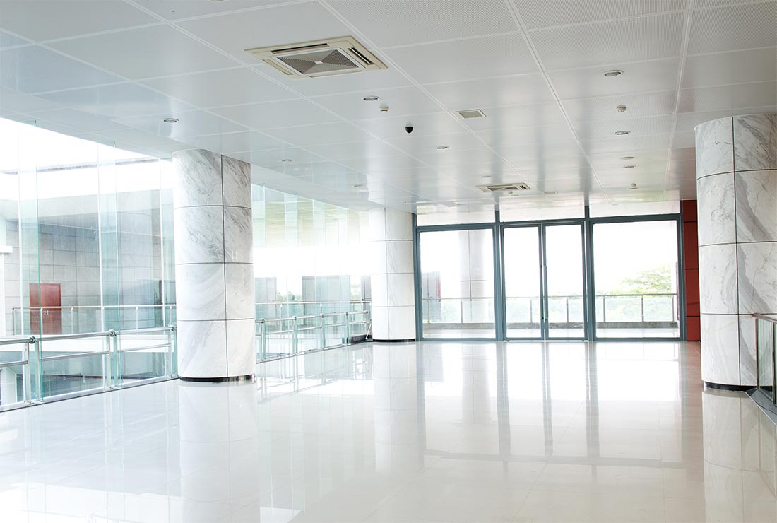 Modern showroom interior featuring glossy white floors, marble columns, and large glass windows, suitable for showcasing business projects and services.