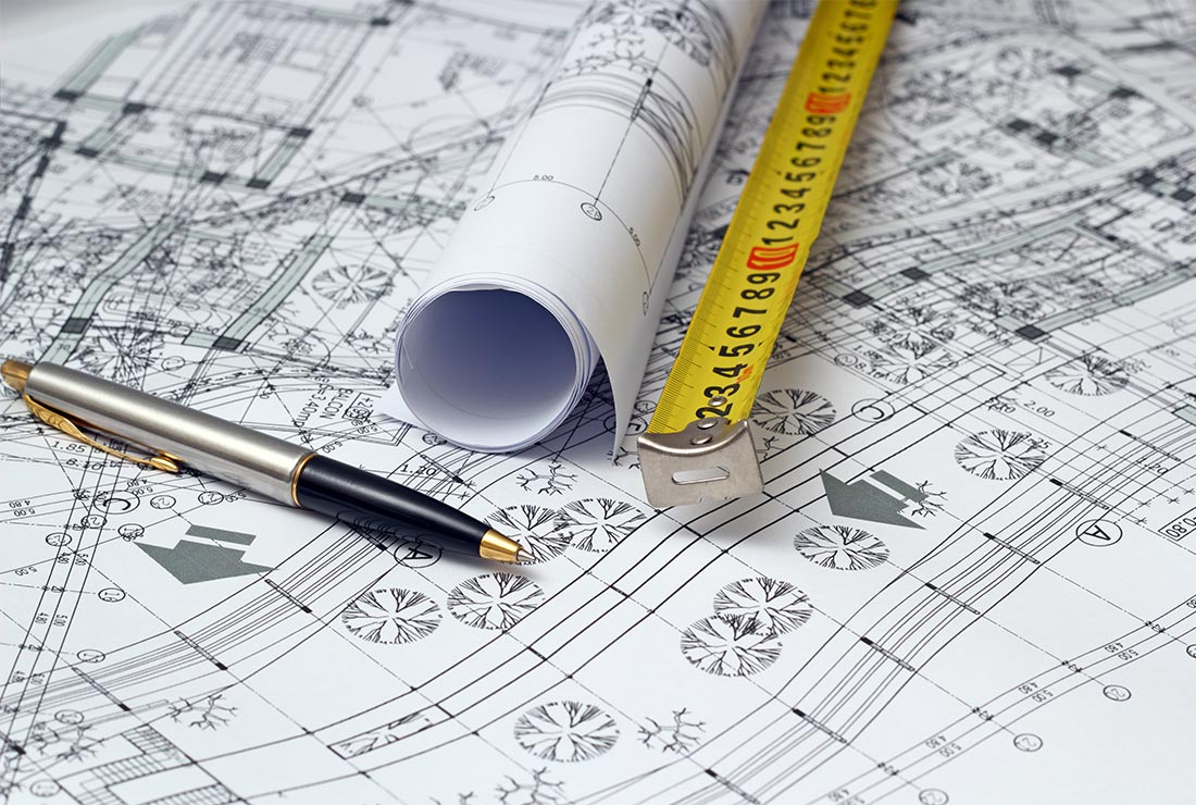 Blueprints with architectural designs, a rolled plan, measuring tape, and a pen, emphasizing art and design in handyman services.