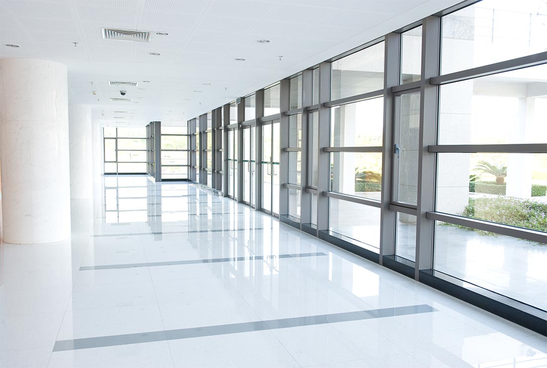 Modern hallway with large windows and polished flooring in a commercial building.