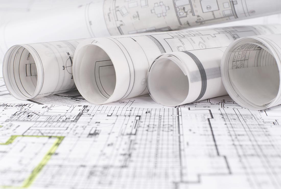 Blueprints and architectural plans rolled up on a table, showcasing detailed designs for construction projects, relevant to Bear Essentials Handyman Services' portfolio.